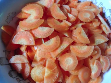 Yeşil arka planda bir kasede patates ve havuç, yakın plan.