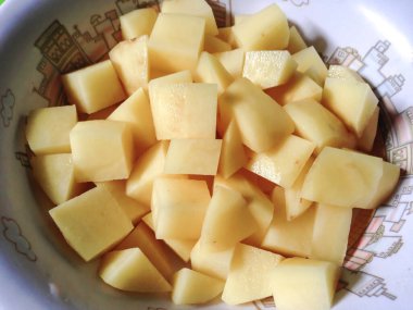 Yeşil arka planda bir kasede patates ve havuç, yakın plan.