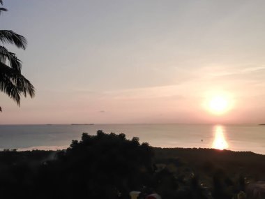 Glasses on table. Palm tree and sunset on the tropical island of Karimunjawa, indonesia.