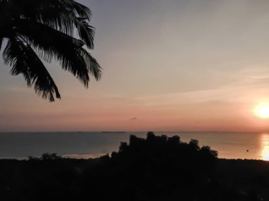 Glasses on table. Palm tree and sunset on the tropical island of Karimunjawa, indonesia.
