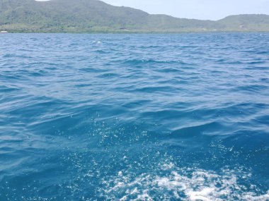 Güneşli bir günde tekneden güzel bir deniz manzarası. Pasifik Okyanusu Dağı arka planı. Denizin yüzeyindeki deniz dalgaları. 