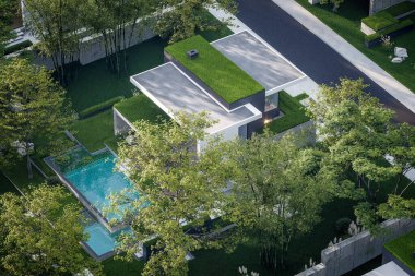 Otoparkı ve havuzu satılık ya da kiralık, beton cepheli ve güzel peyzajlı 3 boyutlu çatı evi. Pencerenin sıcacık ışıklarıyla berrak bir yaz akşamı