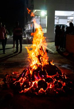 Tanımlanamayan insanlar, Hindu festivali Lohri 'yi kutluyorlar. Holika Dahan' daki şenlik ateşiyle Hint geleneği için ahşap yakılıyor..