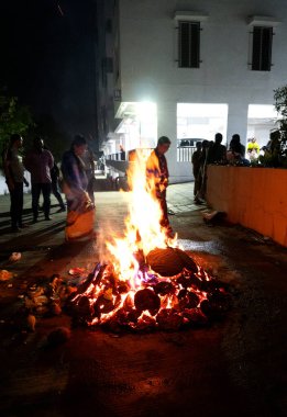 Tanımlanamayan insanlar, Hindu festivali Lohri 'yi kutluyorlar. Holika Dahan' daki şenlik ateşiyle Hint geleneği için ahşap yakılıyor..