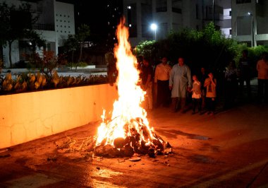 Tanımlanamayan insanlar, Hindu festivali Lohri 'yi kutluyorlar. Holika Dahan' daki şenlik ateşiyle Hint geleneği için ahşap yakılıyor..