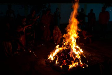 Tanımlanamayan insanlar, Hindu festivali Lohri 'yi kutluyorlar. Holika Dahan' daki şenlik ateşiyle Hint geleneği için ahşap yakılıyor..