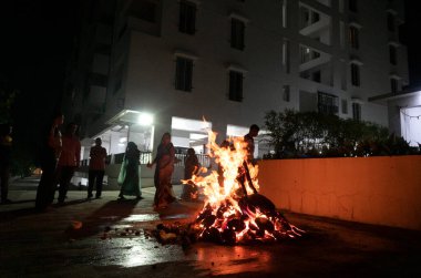 Tanımlanamayan insanlar, Hindu festivali Lohri 'yi kutluyorlar. Holika Dahan' daki şenlik ateşiyle Hint geleneği için ahşap yakılıyor..