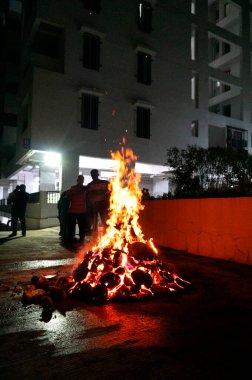 Tanımlanamayan insanlar, Hindu festivali Lohri 'yi kutluyorlar. Holika Dahan' daki şenlik ateşiyle Hint geleneği için ahşap yakılıyor..