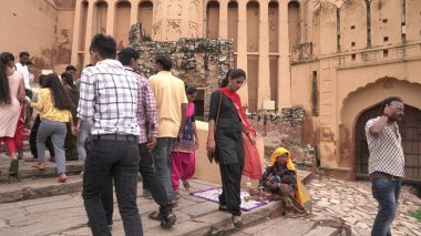 JAIPUR, INDIA 14 AĞUSTOS 2019: Çocuklu bir kadın Amber kalesinde oturuyor ve turistlere alfabe boncukları satıyor.