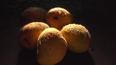 Stüdyo görüntüleri. Karanlıkta taze mango meyvelerine su püskürtürken.