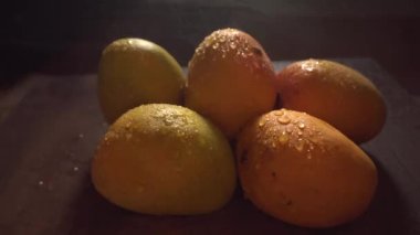 Stüdyo görüntüleri. Karanlıkta taze mango meyvelerine su püskürtürken.
