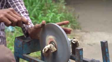 man sharpening knife on machine outdoors