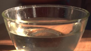 falling fresh sweet sliced carrot into the glass bowl with water, close up view