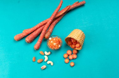 Taze ve lezzetli havuçlar, mavi arka planda kaju ve badem.