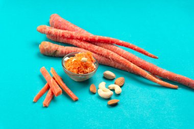 Taze ve lezzetli havuçlar, mavi arka planda kaju ve badem.