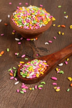 colorful candies in bowl and spoon on the wooden table