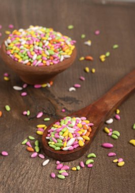 colorful candies in bowl and spoon on the wooden table