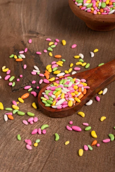 colorful candies in bowl and spoon on the wooden table