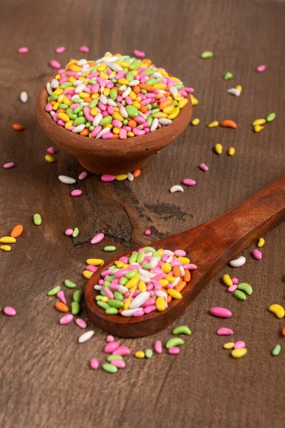 colorful candies in bowl and spoon on the wooden table