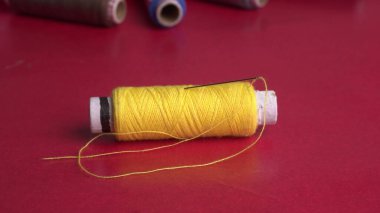 sewing threads and needle on a red background