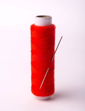 Beyaz zemin üzerinde iğne olan kırmızı dikiş ipliği