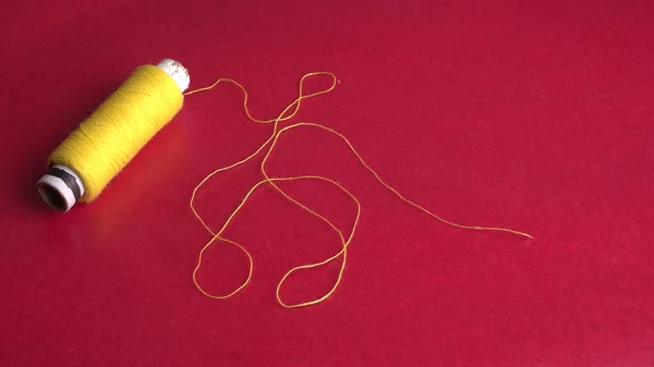 yellow sewing thread on red background