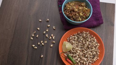 close up view of raw and prepared sprouted soy in bowls with towel, lemon and peppers, healthy food concept