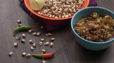 close up view of raw and prepared sprouted soy in bowls with towel, lemon and peppers, healthy food concept