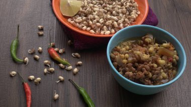 close up view of raw and prepared sprouted soy in bowls with towel, lemon and peppers, healthy food concept