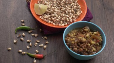 close up view of raw and prepared sprouted soy in bowls with towel, lemon and peppers, healthy food concept