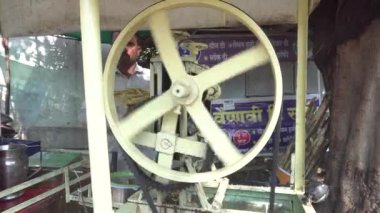 Udaipur, Hindistan - 5 Mart 2018: Hintli adam şeker kamışından şeker suyu sıkmak için eski bir makine kullanıyor