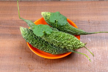 fresh green momordica charantia or bitter melon on wooden surface