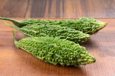 fresh green momordica charantia or bitter melon on wooden surface