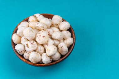 Organik gevrek nilüfer tohumu veya fool makhana 'yı mavi arka planda kasede patlatır.