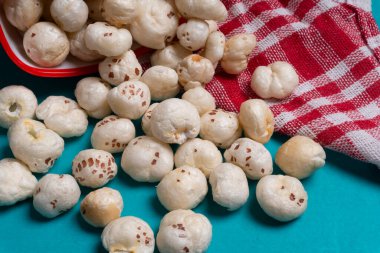 Organik gevrek nilüfer tohumu veya fool makhana 'yı mavi arka planda kasede patlatır.