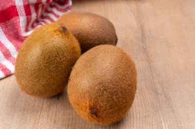 Tahta yüzeyde havlusu olan taze kivi meyveleri.