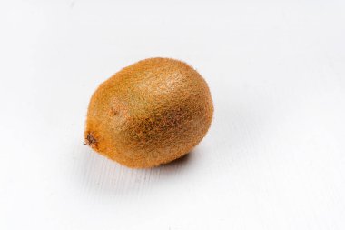 Tüm kivi meyvesi beyaz ahşap arka planda, yakın plan.