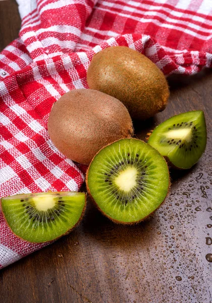 Tahta yüzeyde havlusu olan taze kivi meyveleri.