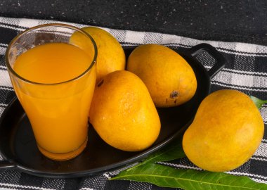 Olgun sarı mango meyvesi ve bir bardak meyve suyu.