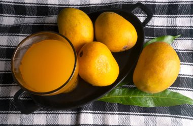 Olgun sarı mango meyvesi ve bir bardak meyve suyu.