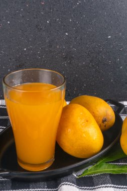 Olgun sarı mango meyvesi ve bir bardak meyve suyu.