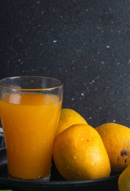 Olgun sarı mango meyvesi ve bir bardak meyve suyu.