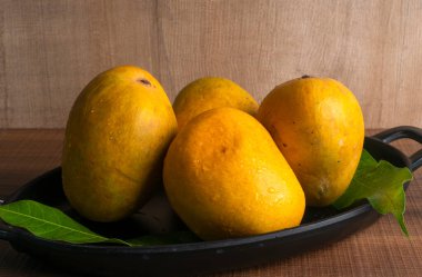 Tahta arka planda olgun sarı mango meyvesi