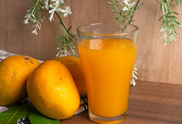 熟した黄色のマンゴーの実をグラスジュースで木の背景に — ストック写真
