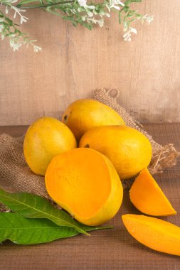 Tahta arka planda olgun sarı mango meyvesi