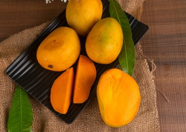 Tahta arka planda olgun sarı mango meyvesi