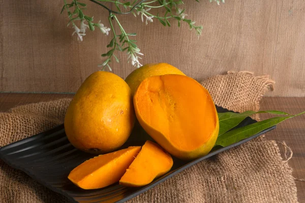 Tahta arka planda olgun sarı mango meyvesi