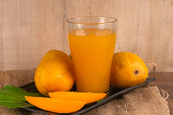熟した黄色のマンゴーの実をグラスジュースで木の背景に — ストック写真