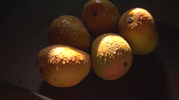 熟した黄色のマンゴーの果実水が暗闇の中で落ちる — ストック動画