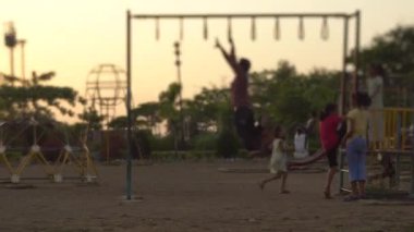 Genç Hintli adam gün batımında parka tırmanıyor.